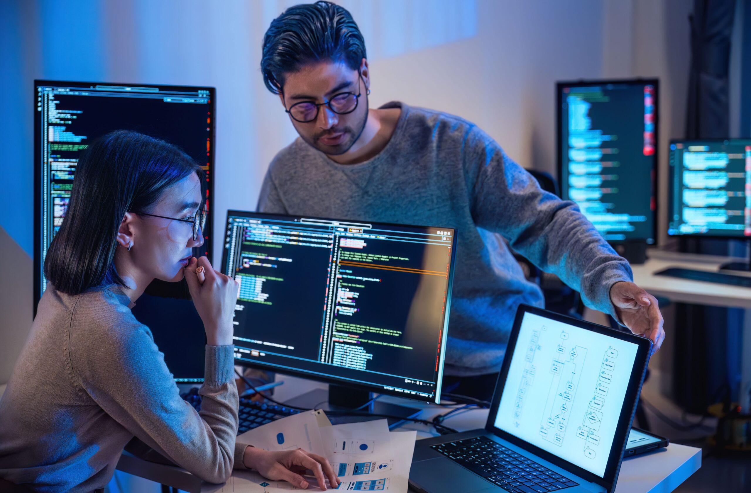 Zwei Entwickler analysieren Code und Daten auf mehreren Bildschirmen