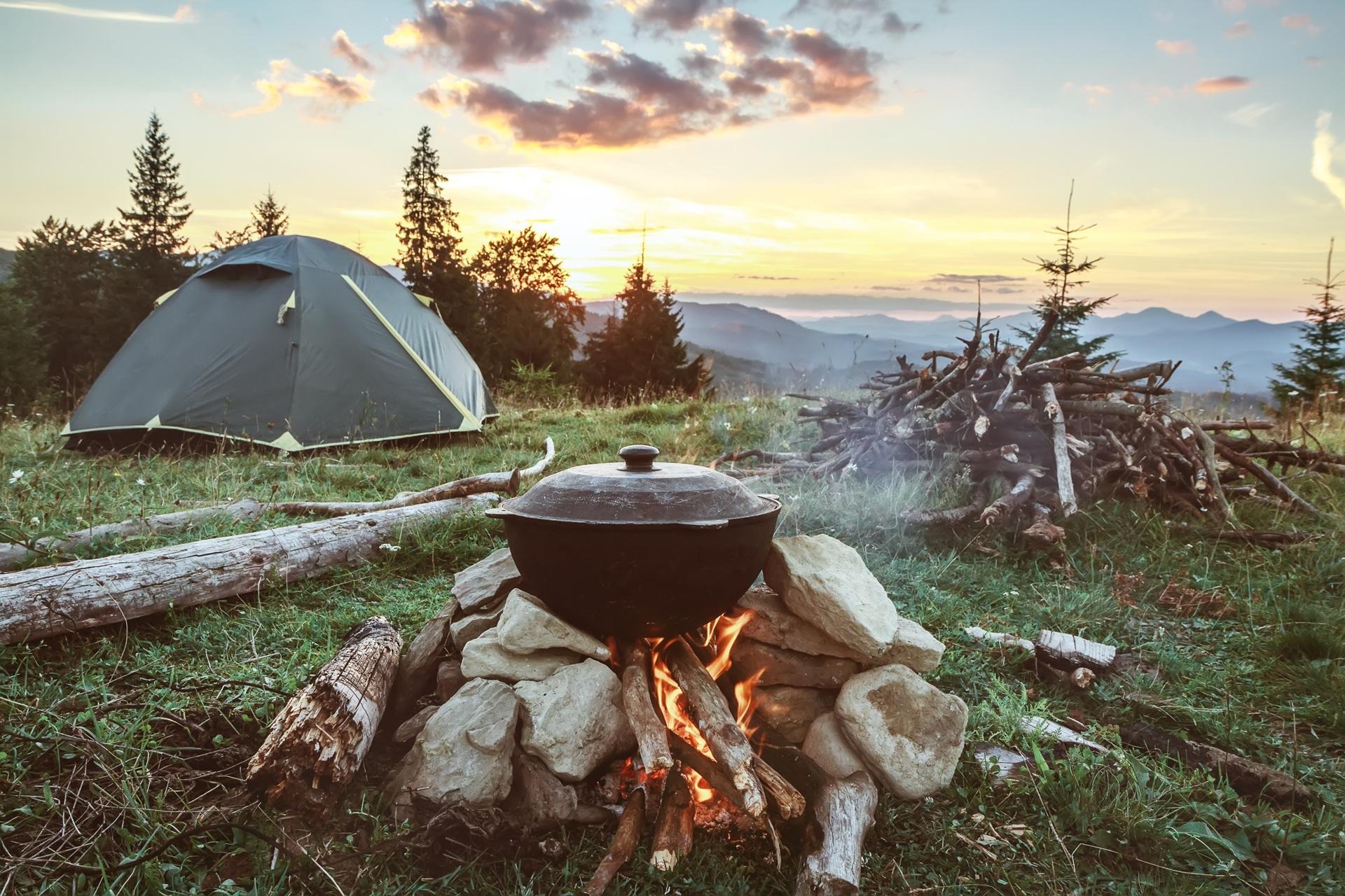 Lagerfeuer mit Kochtopf vor Zelt und Bergen | Petroleum Heizung Camping
